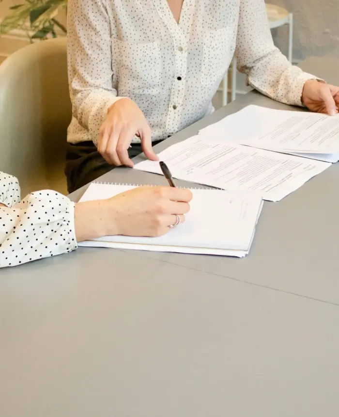 Dos mujeres revisando y firmando documentos de adopción juntas en un escritorio
