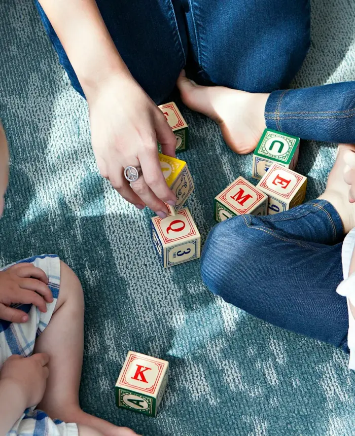 Dos niños pequeños jugando con cubos de letras en el piso